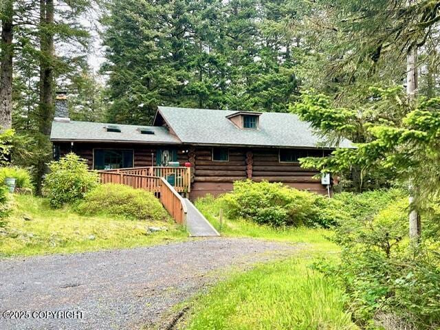 log cabin with driveway and log siding