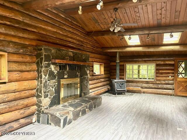 unfurnished living room with wooden ceiling, wood finished floors, vaulted ceiling with beams, a wood stove, and log walls