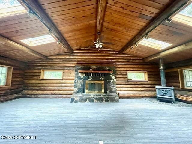 interior space with a wood stove, rail lighting, a fireplace, and beamed ceiling