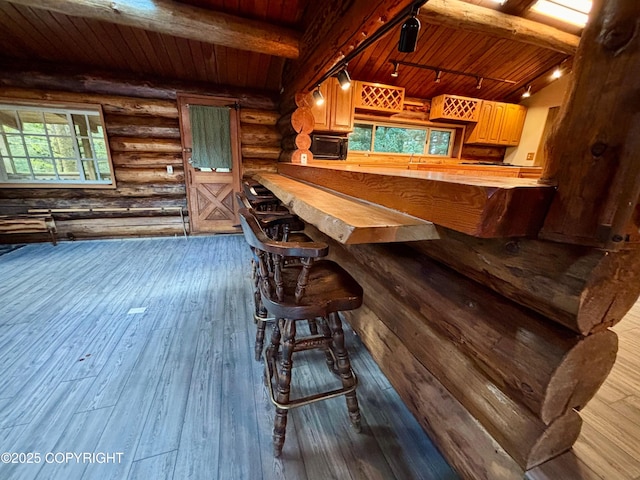 bar featuring rustic walls, wooden ceiling, hardwood / wood-style floors, beamed ceiling, and rail lighting