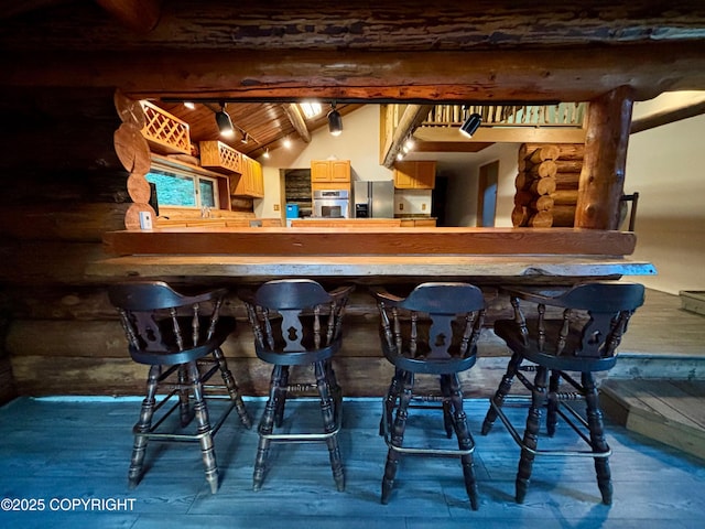 bar with wood ceiling, stainless steel appliances, log walls, and vaulted ceiling with beams