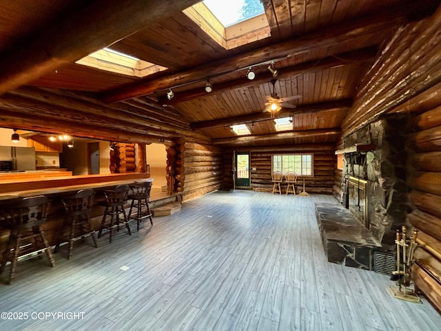 bar featuring lofted ceiling with beams, wood-type flooring, refrigerator, a fireplace, and track lighting