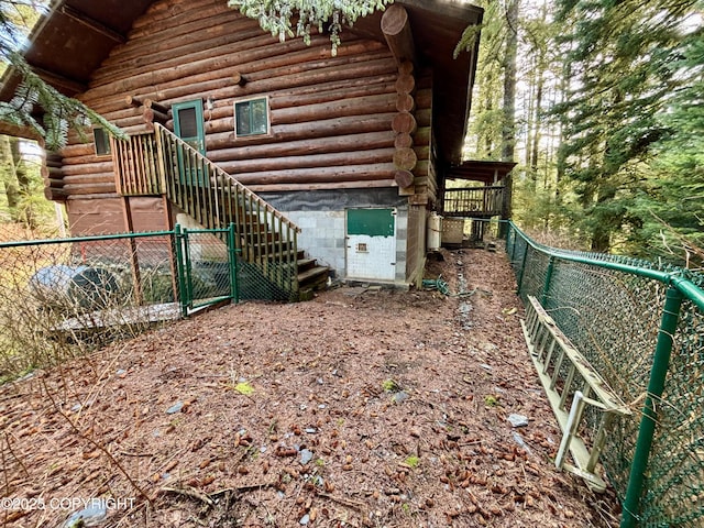 view of side of home featuring log siding and fence