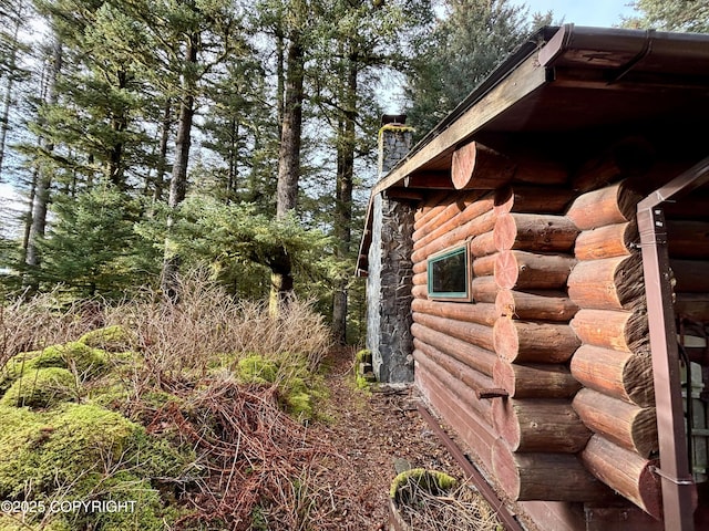 view of side of property featuring a chimney and log siding