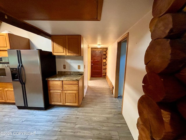 kitchen with dark countertops, stainless steel refrigerator with ice dispenser, wall oven, and light wood-style flooring