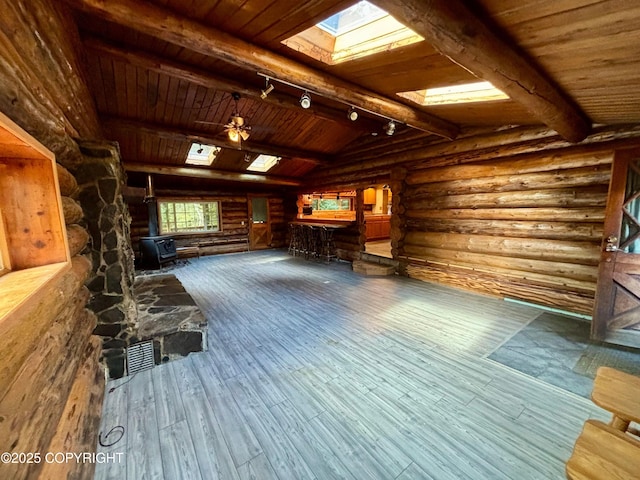 interior space featuring lofted ceiling with skylight, wooden ceiling, rustic walls, and hardwood / wood-style flooring