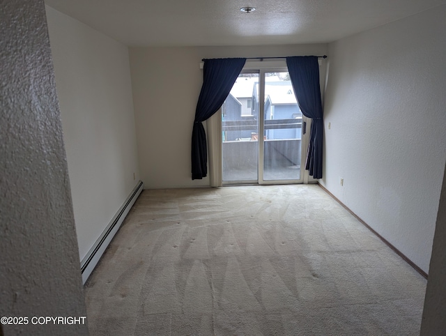 empty room featuring a baseboard heating unit, carpet, and a textured wall