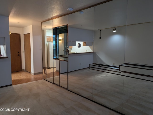 interior space with carpet floors, a textured ceiling, and freestanding refrigerator