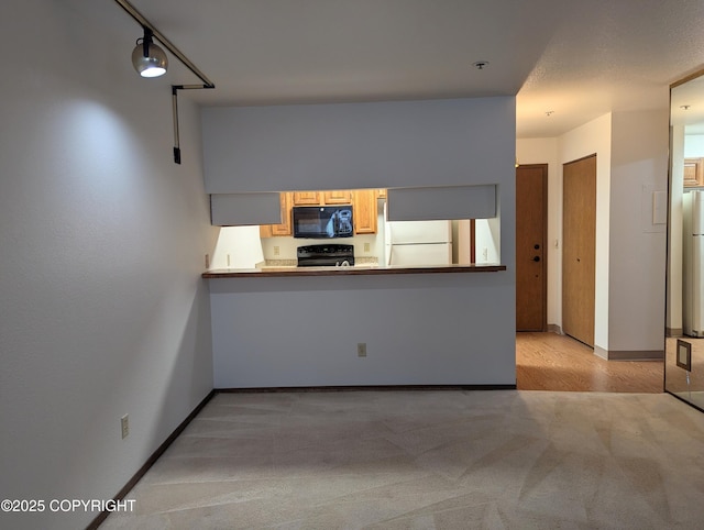 kitchen featuring black appliances, a peninsula, and baseboards