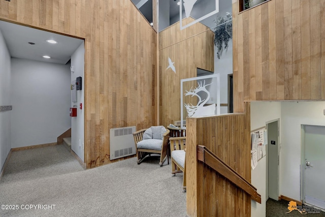 sitting room with radiator, carpet, and wood walls