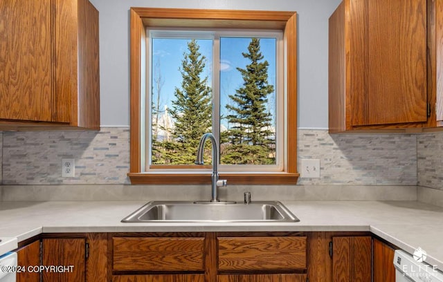 kitchen with brown cabinetry, a sink, and light countertops