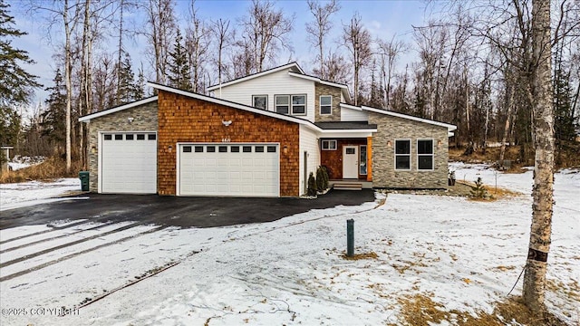 view of front of home featuring stone siding, aphalt driveway, and an attached garage