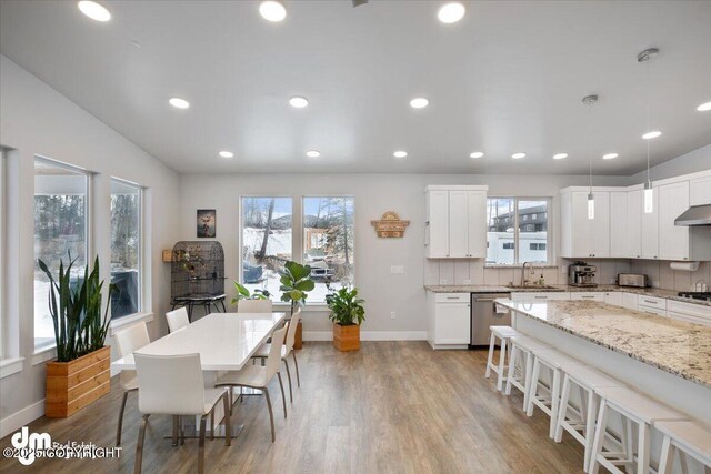 kitchen featuring dishwasher, tasteful backsplash, light wood finished floors, and a kitchen breakfast bar