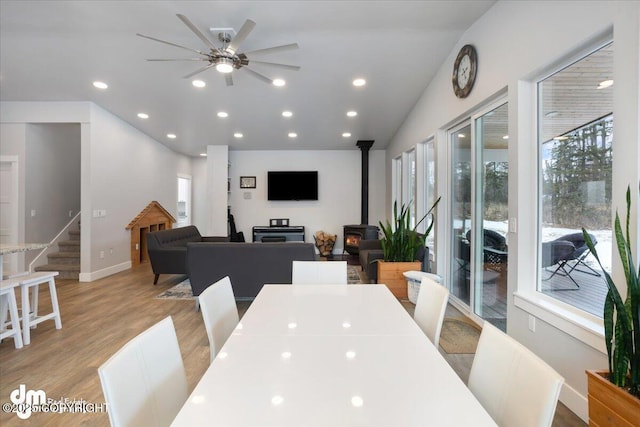 dining room with stairs, light wood finished floors, a wood stove, and recessed lighting