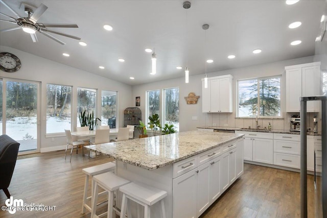 kitchen featuring lofted ceiling, a center island, a sink, and wood finished floors