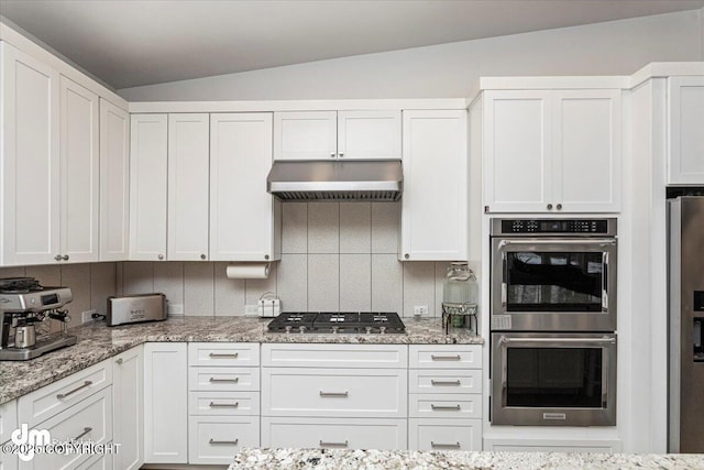 kitchen with stainless steel appliances, white cabinets, under cabinet range hood, and light stone countertops