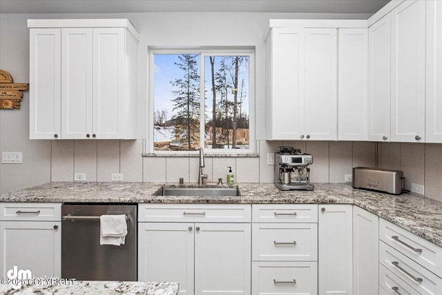 kitchen featuring light stone counters, a sink, white cabinetry, dishwasher, and tasteful backsplash