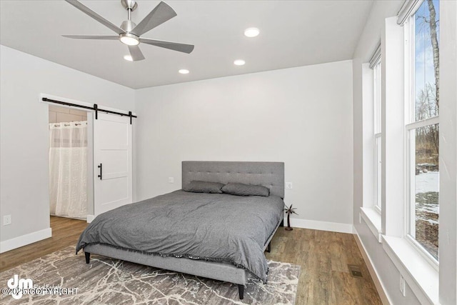 bedroom featuring wood finished floors, baseboards, and a barn door