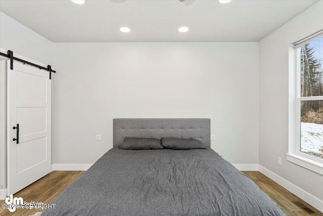 bedroom with wood finished floors, baseboards, and a barn door