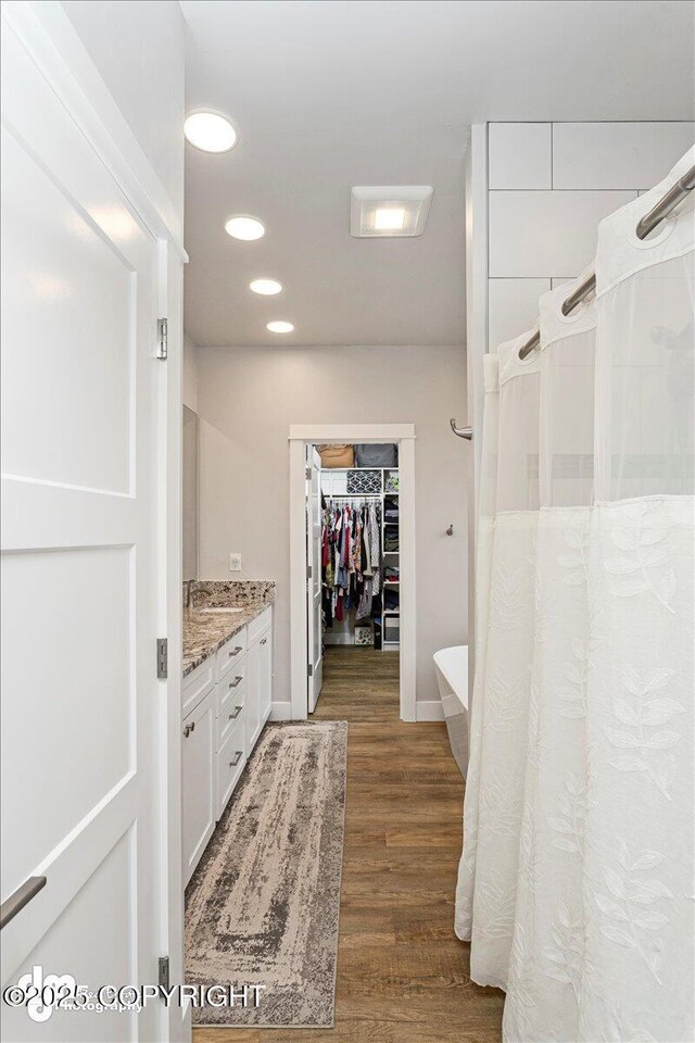 bathroom featuring recessed lighting, wood finished floors, vanity, a spacious closet, and a shower with curtain