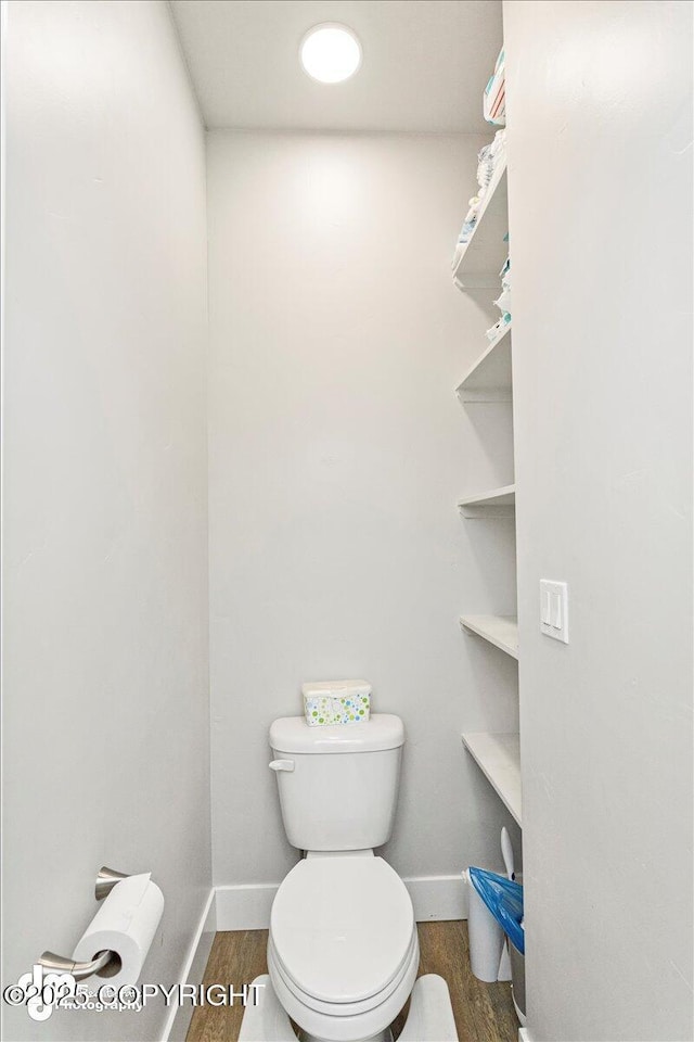 bathroom with baseboards, toilet, and wood finished floors