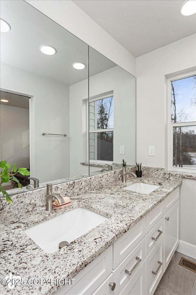 bathroom with plenty of natural light, visible vents, a sink, and double vanity