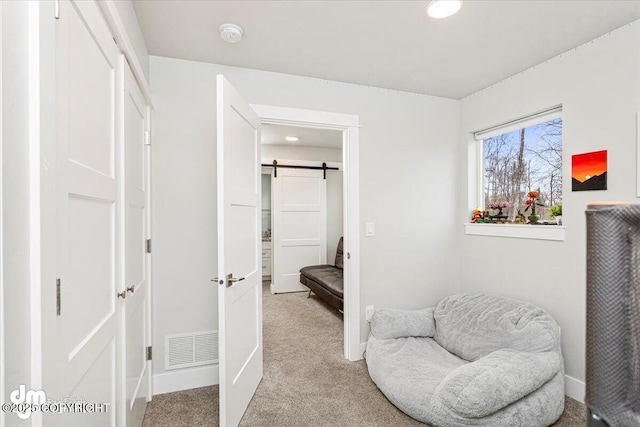 living area featuring light carpet, a barn door, visible vents, and baseboards