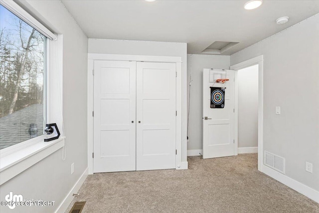 unfurnished bedroom with a closet, carpet flooring, visible vents, and baseboards