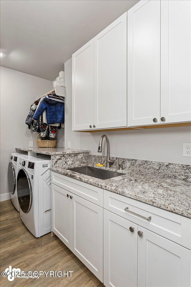 washroom with washer and clothes dryer, light wood-type flooring, a sink, and cabinet space