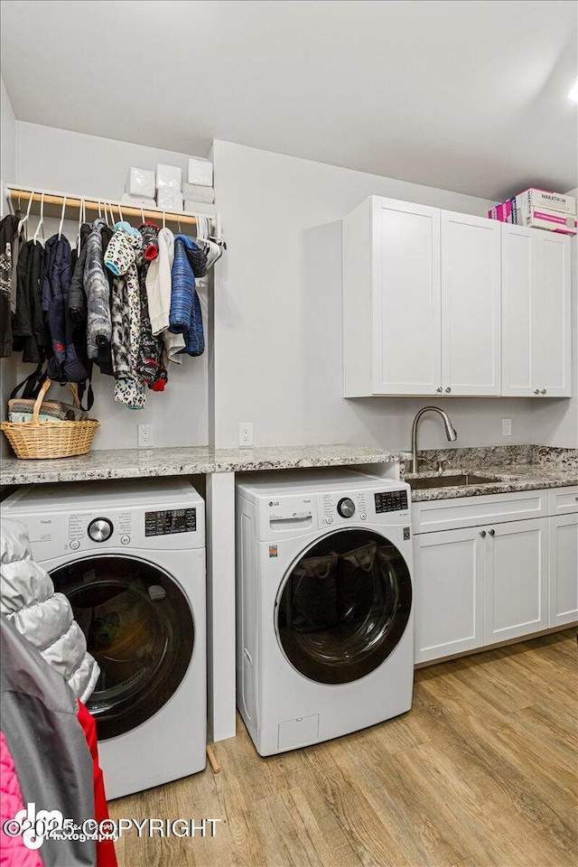 laundry room featuring a sink, washing machine and clothes dryer, cabinet space, and light wood-style floors