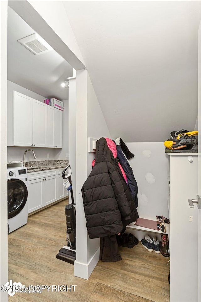 washroom featuring washer / clothes dryer, visible vents, cabinet space, light wood-style flooring, and a sink