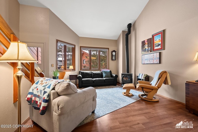 living area with a wood stove, baseboards, vaulted ceiling, and wood finished floors