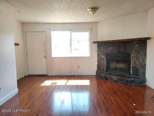 7811 Kiana Cir, Anchorage, AK 99507 - unfurnished living room with wood finished floors, baseboards, a fireplace, and a textured ceiling