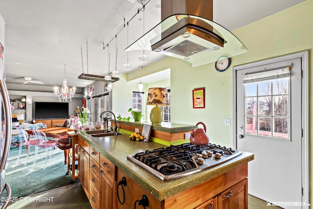 kitchen featuring a kitchen island with sink, stainless steel gas stovetop, brown cabinets, and a sink