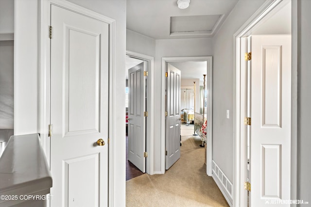 corridor with light carpet and attic access