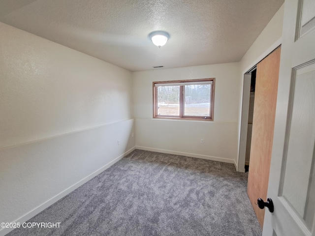 unfurnished bedroom featuring visible vents, baseboards, a textured ceiling, carpet floors, and a closet