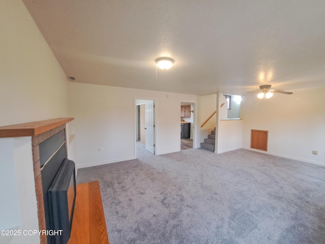 unfurnished living room with carpet floors, a fireplace, stairway, a textured ceiling, and baseboards