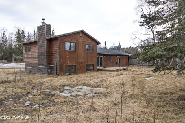 back of property featuring a chimney, fence, and a wooden deck