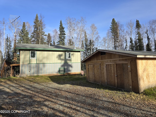 view of side of home featuring stairs, a storage shed, and an outdoor structure