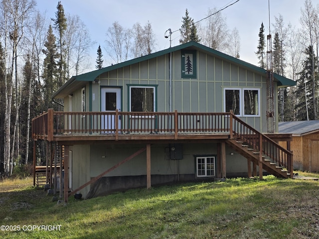 back of property featuring a deck, a lawn, and stairway