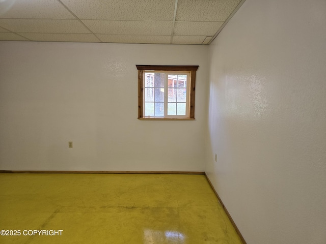 unfurnished room with a paneled ceiling and baseboards