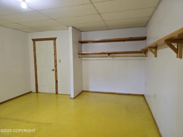 interior space featuring a paneled ceiling and baseboards