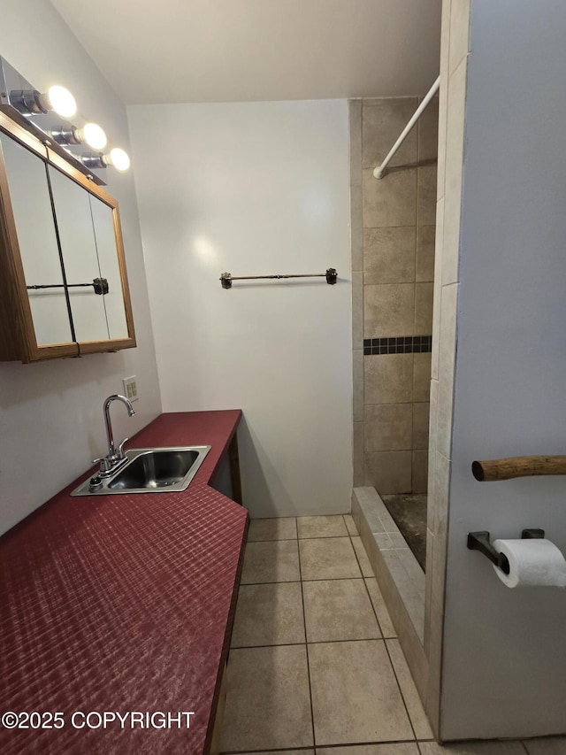 bathroom featuring tiled shower, tile patterned flooring, and a sink