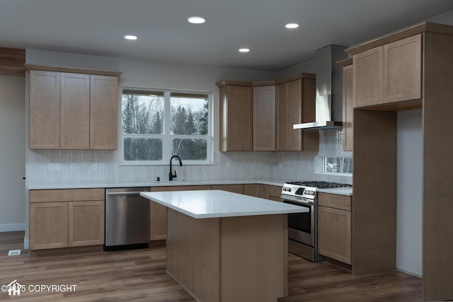 kitchen featuring decorative backsplash, stainless steel appliances, light countertops, wall chimney range hood, and a sink