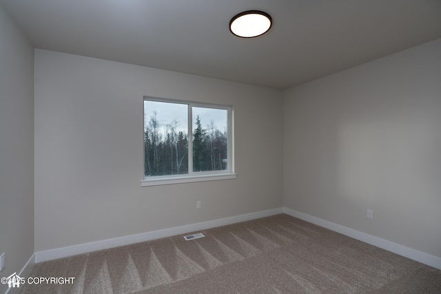 carpeted empty room featuring baseboards and visible vents