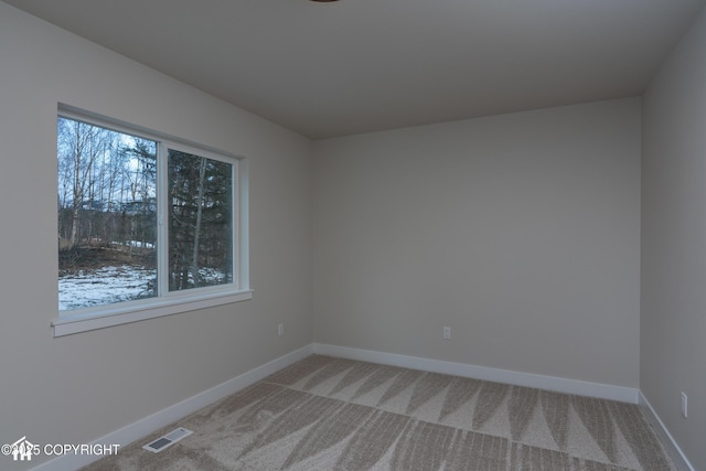 empty room featuring visible vents, light carpet, and baseboards