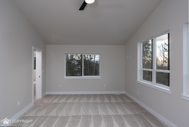 interior space featuring ceiling fan, baseboards, vaulted ceiling, and light colored carpet