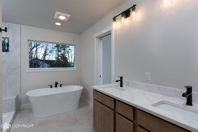 full bathroom featuring double vanity, a freestanding tub, and a sink