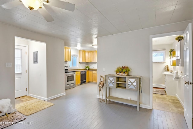 kitchen with black dishwasher, baseboards, stainless steel range with electric cooktop, light wood-type flooring, and light brown cabinets