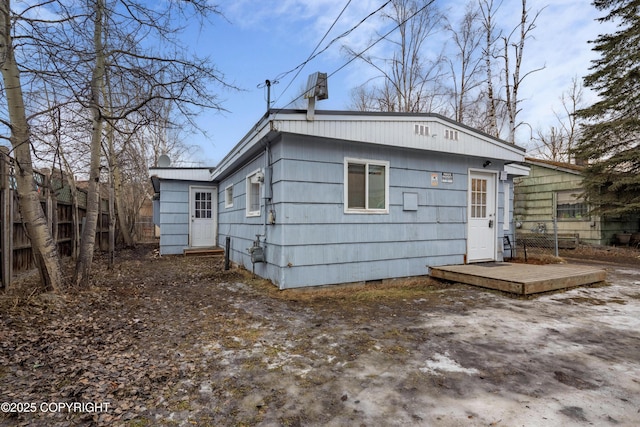 rear view of house with a chimney and fence